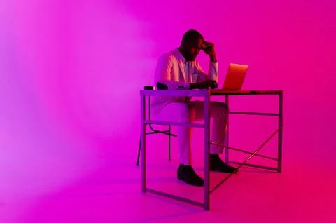 A man is sitting at a desk. A black programmer works using a laptop compute.. Stock Photos