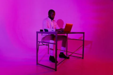 A man is sitting at a desk. A black programmer works using a laptop compute.. Stock Photos