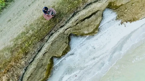 Man sitting at a desk with a computer at the cliff by the sea. Rise drone Stock Footage 65463684
