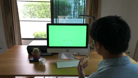 A man is sitting at a desk with a green screen in front of him Stock Footage 318938146
