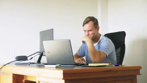 A man sitting at a desk at home, working at home computer and laptop. 스톡 동영상 106689488
