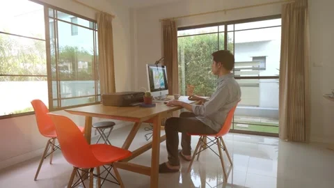 A man is sitting at a desk in a room with a computer monitor and a printer Stock Footage 318938096