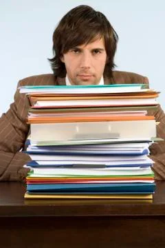 Man sitting on desk with stack of files, portrait Stock Photos