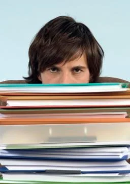 Man sitting on desk with stack of files, portrait, high section, close-up 스톡 사진