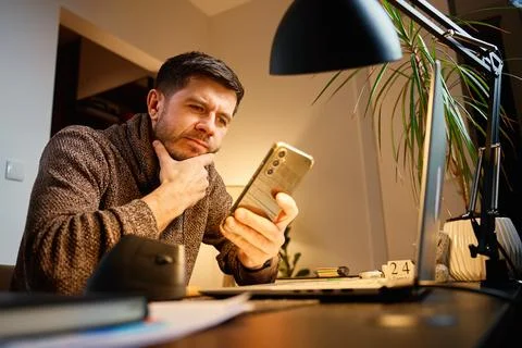 Man sitting at desk using smartphone in home office Stock Photos