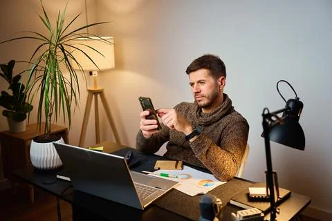 Man sitting at desk using smartphone in home office Stock Photos