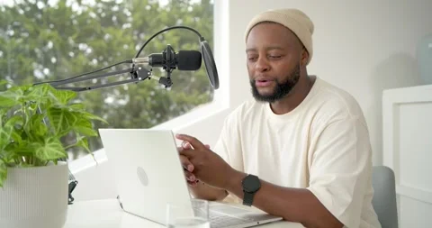 Man sitting at desk by window, starting recording into boom mic, laptop open, Stock Footage 338168415
