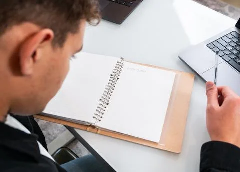 Man sitting at desk writing in a notebook Stock Photos