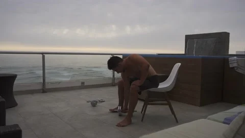 A man sitting doing biceps curl exercises with dumbbells on the terrace of a 스톡 동영상 186209629