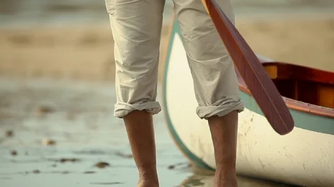 Man sitting down on a boat pulled up on a beach. Stock-Footage 88342918