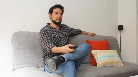 Man sitting down in a couch and turning on a smart tv with a remote controller Vídeo Stock 340583403