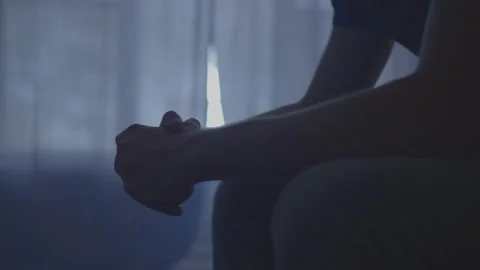 Man Sitting Down in a Dark Room Rubbing His Hands Together Stock Footage 208786343