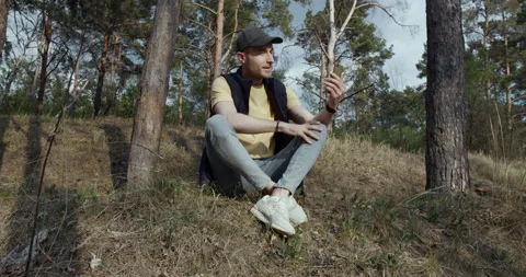 A man sitting down on the grass in the park, talking video call Stock Footage 139206413