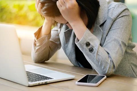 A man sitting down, his face unsettled. At the computer desk He has headaches Stock Photos