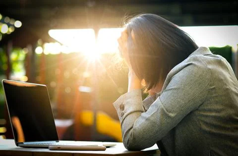 A man sitting down, his face unsettled. At the computer desk He has headaches Stock Photos