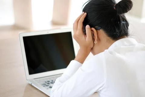 A man sitting down, his face unsettled. At the computer desk He has headaches Stock Photos