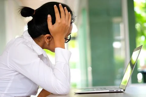 A man sitting down, his face unsettled. At the computer desk He has headaches Stock Photos