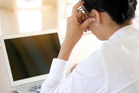 A man sitting down, his face unsettled. At the computer desk He has headaches Stock Photos