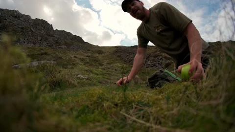A man sitting down on mountain grass with an apple Vidéo 192467599