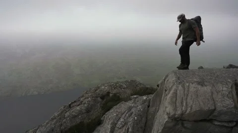 A man sitting down in the mountains for a rest in misty weather Stock Footage 141663001