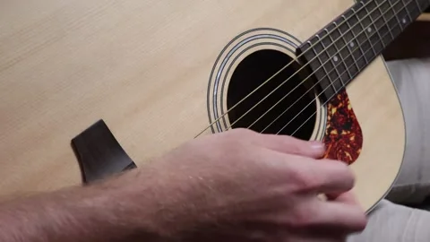Man sitting down strumming his guitar with a pick Stock Footage 279909194
