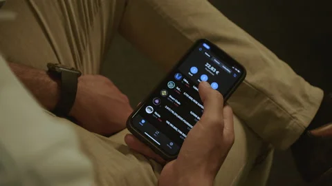 Man sitting down while scrolling the Trust Wallet app Video stock 160474098