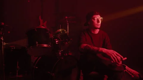 Man Sitting by Drum Kit Using Smartphone in Music Studio Stock Footage 338396023