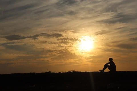 Man sitting during sunset Stock Photos