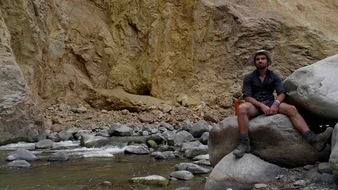 A man sitting on the edge of the Canyon of the Colca River in southern Peru Stock Footage 125287299