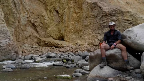 A man sitting on the edge of the Canyon of the Colca River in southern Peru Stock Footage 125287312