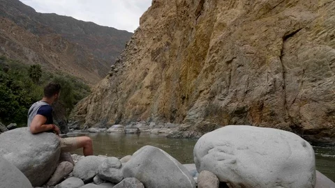 A man sitting on the edge of the Canyon of the Colca River in southern Peru Stock Footage 125287329