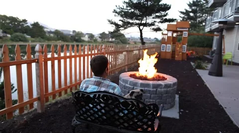 Man sitting at a fire pit on a bench with a pug Stock Footage 41755973