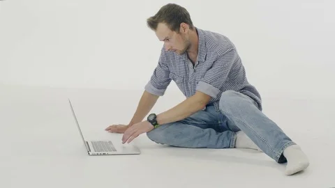 Man sitting on the floor and typing  on a laptop isolated on white background. 스톡 동영상 80319446