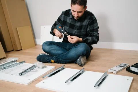 Man sitting on the floor assembling a piece of furniture. do it yourself Stock Photos