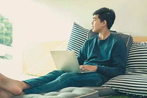 Man sitting on floor using computer at home. male teenager student studying d Stock Photos