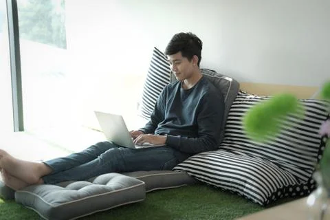 Man sitting on floor using computer at home. male teenager student studying d Stock Photos