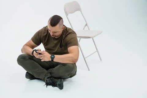 Man Sitting on Floor Using Smartphone in Casual Clothing Stock Photos