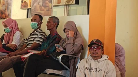 Man Sitting On Floor In Waiting Room With Masked People On Chairs Stock Footage 340030934