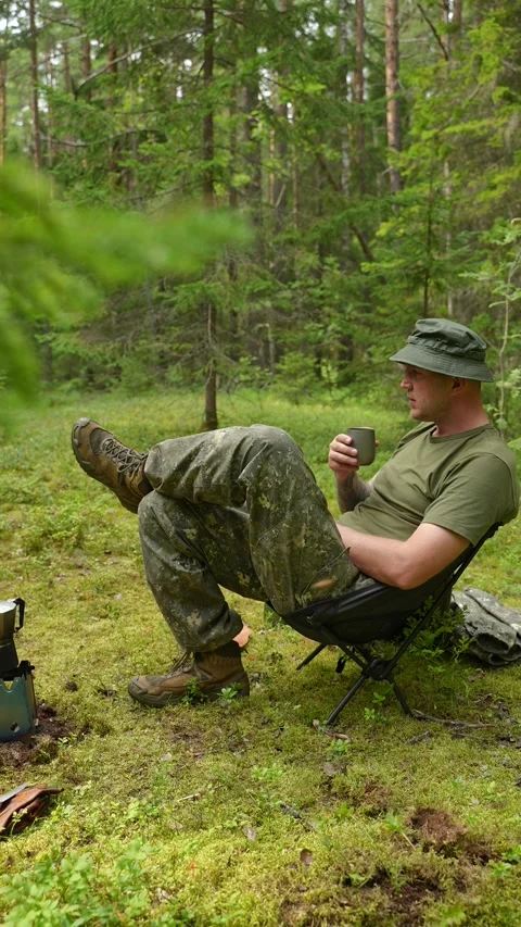 Man sitting in a folding chair and drinking hot coffee from a mug Stock Footage 340653871