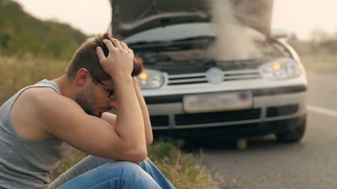 Man sitting in a front of broken car Stock Footage 79213324