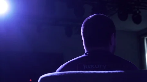 Man sitting in front of spotlight from behind Video stock 129639866