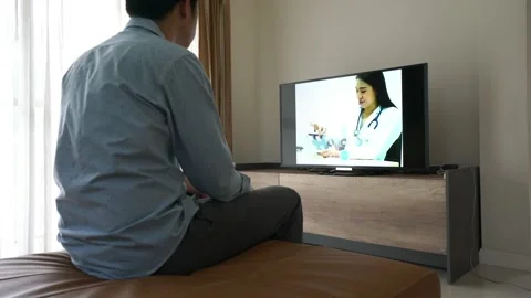 A man is sitting in front of a television has tele HealthCare with a doctor on a Stock Footage 314639697