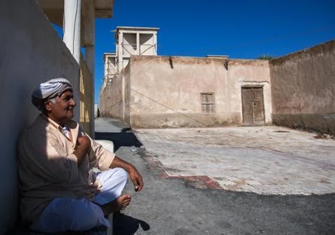 Man sitting in front of a wind tower, Hormozgan, Bandar-e Kong, Iran Stock Photos