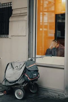 A man is sitting in front of a window with a backpack and a stroller Stock Photos
