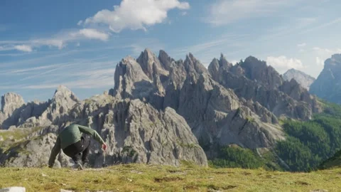Man sitting on grass and admiring mountain peaks in Dolomites Italy Stock Footage 320178962
