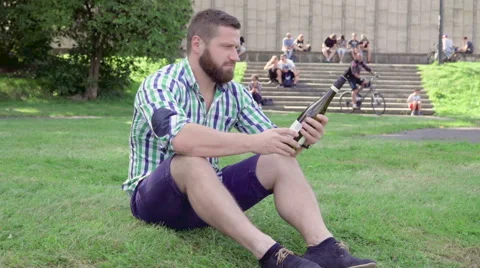 Man sitting on grass, looking over bottle of wine. Steadicam. Vidéo 67238936