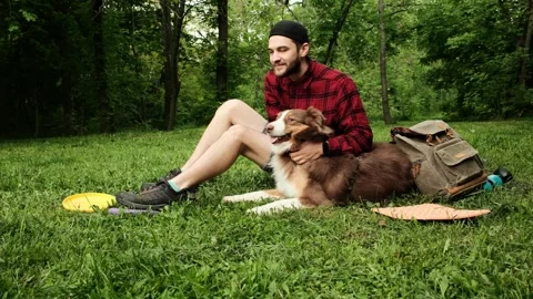 Man sitting on the grass in the park, hugging and kissing his Australian Stock Footage 319930442