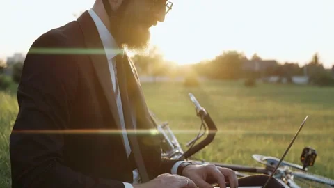 Man sitting on a grass at the park working on a laptop, wearing a helmet Stock-Footage 163350835