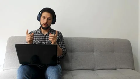 Man sitting on a grey couch in a video meeting job on a remote working concept Vídeo Stock 340583330
