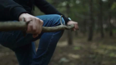 Man Sitting On The Ground Breaks Tree Branches Using His Knee Cap Stock Footage 180269220